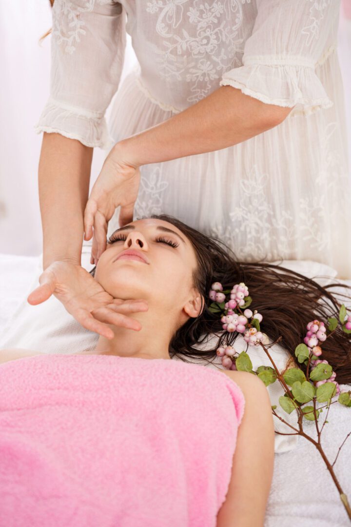 Woman receiving a relaxing facial massage with flowers.