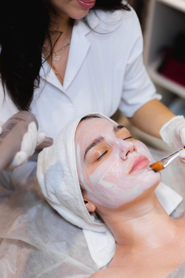 Woman receiving a facial treatment with a brush at a spa.